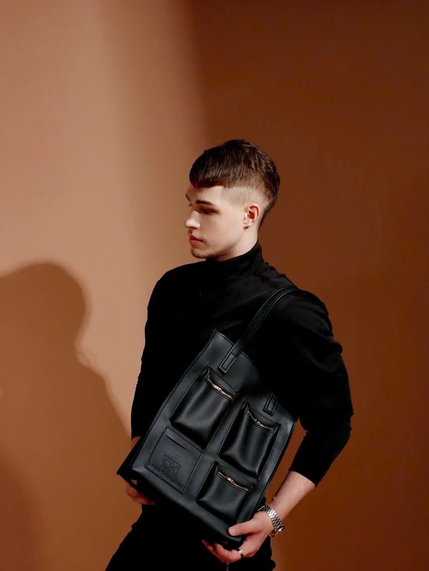In profile against a brown studio wall, a model carries the DK 01 Moscow tote over the shoulder.